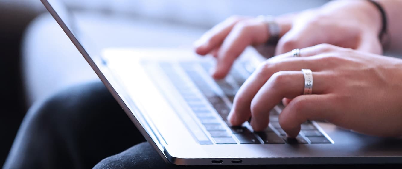 Notebook mit tippenden Händen symbolisiert den Kontakt zu eCube aufzunehmen